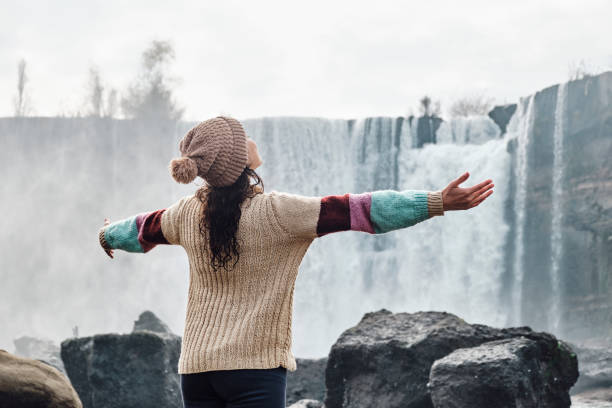 istock young woman with open arms in front of a waterfall 1409337931