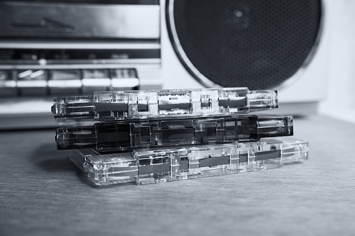 Vintage cassette tapes with radio-cassette player on a wooden table.