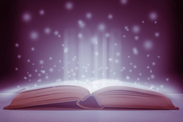 Opened magic book on the table and outgoing mysticism and graphics.