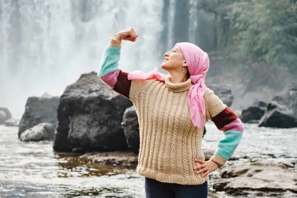 Photo of woman with cancer showing strength with her arms in the open air