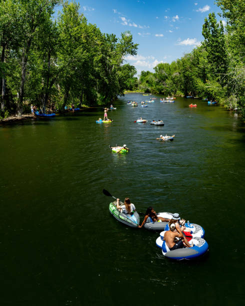 Boise, Idaho, USA – July 16, 2022: Tree lined Boise River in summer with tubers cooling off