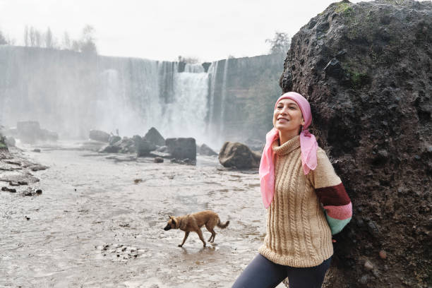 istock young woman with cancer next to a waterfall smiling. 1409341464