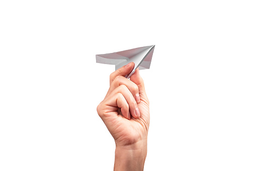 Woman hand throwing origami plane isolated on white background. Handmade flying paper construction. Optimism, childhood concept. High quality photo