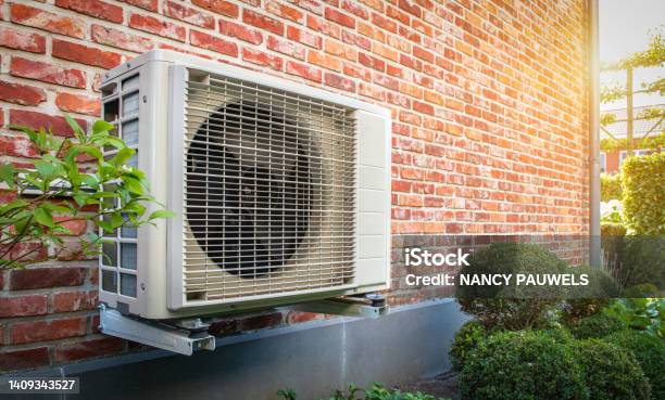 Air Conditioning Heat Pump Outdoor Unit Against Brick Wall Stock Photo - Download Image Now