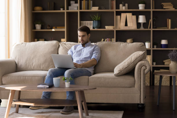 istock Busy young male sit on couch write email on laptop 1409343567