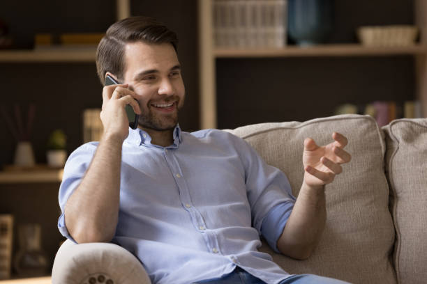 istock Relaxed millennial guy sitting on sofa having nice telephone conversation 1409344243