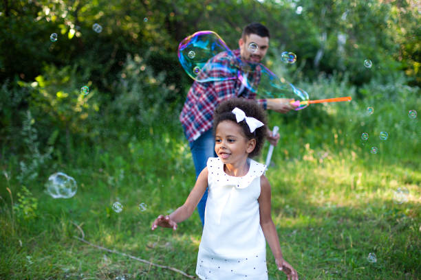 istock Happy father and daughter playing soap bubbles in park. 1409344481