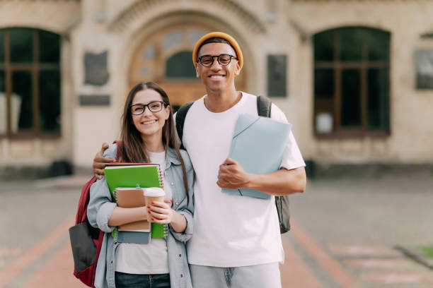 istock Two students standing together near the university, outdoors, looking at the camera 1409345502