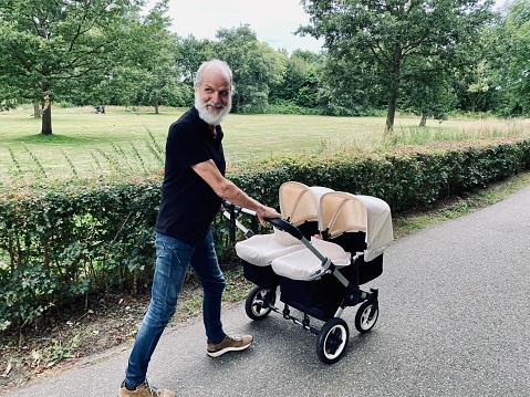 Grandparent walking with his new born boy and girl in the country.
