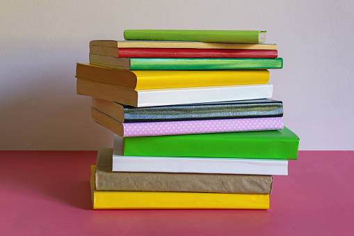 Stack of  different colorful books on table. Space for text
