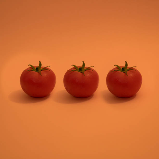 istock Red  tomatoes with green  leaves on orange background. 1409348054