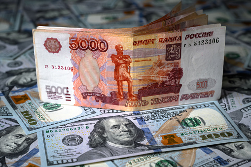Russian ruble money vs US dollar, ruble banknote is on top of dollar bills pile. Concept of sanctions, currency, victory of ruble, economy of Russia and USA, exchange rate, inflation and geopolitics.