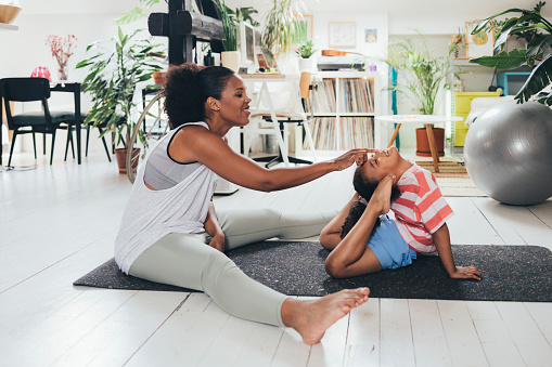 Latin mother and her daughter exercising together at home.