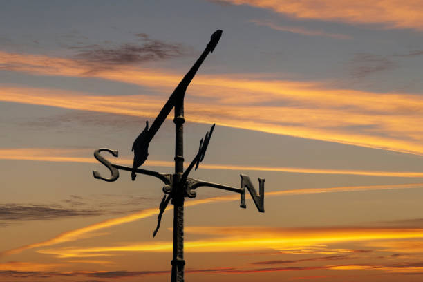 girouette contre le ciel du coucher du soleil - weather vane photos et images de collection