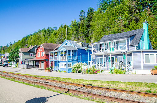 Typical colorful houses along the Chemin du havre in the small town of Pointe au pic in La Malbaie during a nice summer day.\nA railway is in front