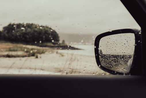 Perspective from a car window of a beach on a rainy day and the scene reflected through a wing mirror.  Holywood, County Down, Northern Ireland.