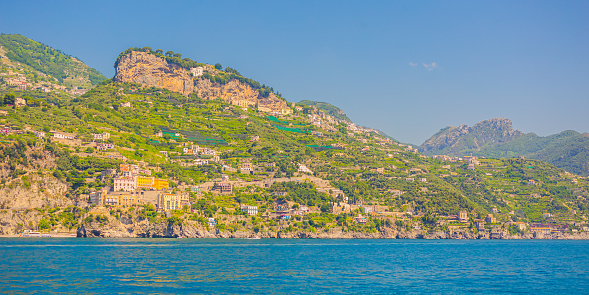 Amalfi coast in Italy on bright sunny day. Beautiful blue expanse of Tyrrhenian Sea. Ancient city. Beach. Mountains. Houses on cliff. Summer trip. Italian architecture. Voyage. Travel destination.