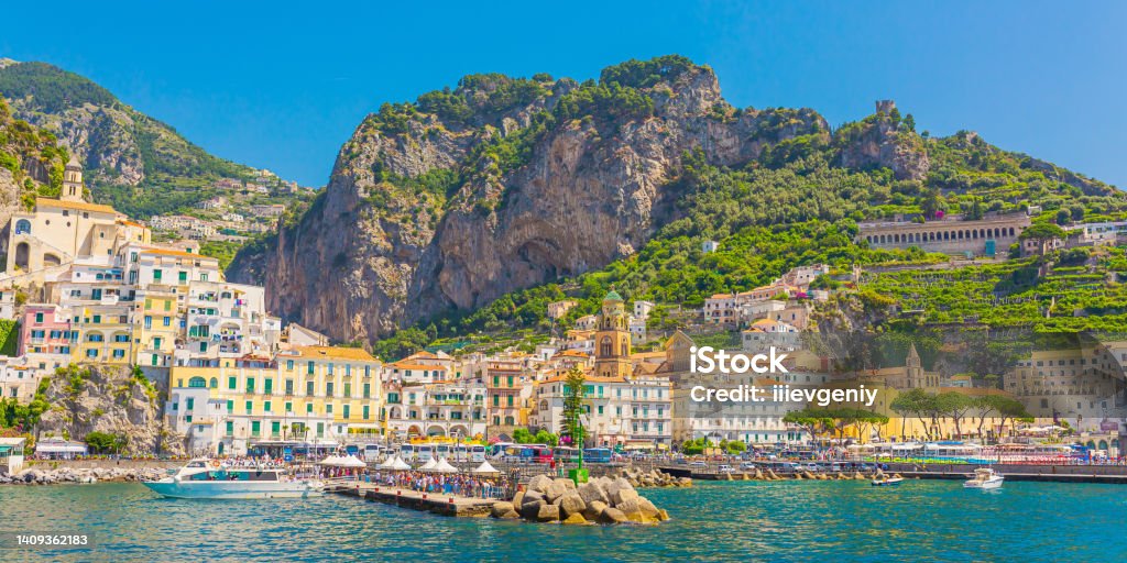 Amalfi coast in Italy on bright sunny day. Beautiful blue expanse of Tyrrhenian Sea. Ancient city. Beach. Mountains. Houses on cliff. Summer trip. Italian architecture. Voyage. Travel destination. Amalfi Coast Stock Photo