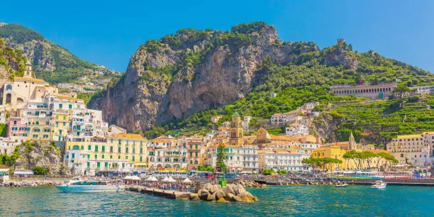 Amalfi coast in Italy on bright sunny day. Beautiful blue expanse of Tyrrhenian Sea. Ancient city. Beach. Mountains. Houses on cliff. Summer trip. Italian architecture. Voyage. Travel destination.