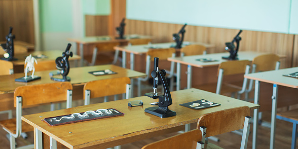 Microscope and animal skeleton on the table. Evolutionary theory. Study biology. Natural Sciences. School desk in class. Classroom. Laboratory at the university. Biolaboratory. Science.