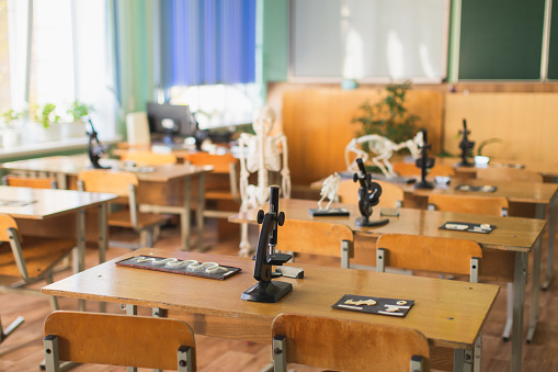 Microscope and animal skeleton on the table. Evolutionary theory. Study biology. Natural Sciences. School desk in class. Classroom. Laboratory at the university. Biolaboratory. Science.