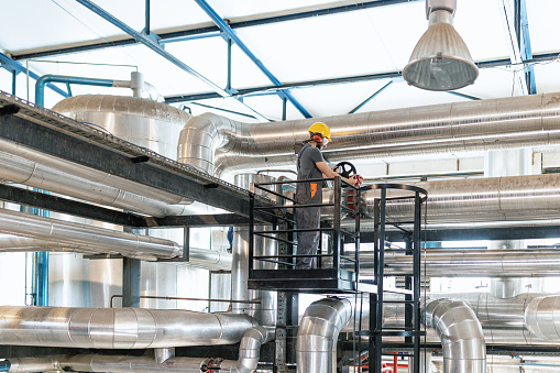 A young Caucasian man wearing protective equipment is working at a modern factory.