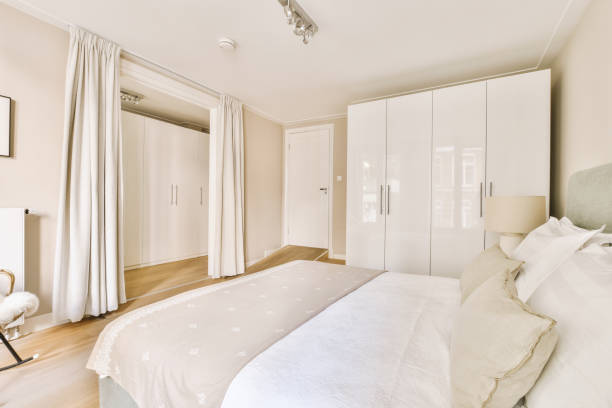 istock Comfortable bed with white wardrobe and armchair 1409370273
