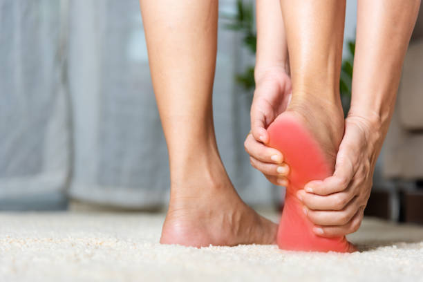 Asian woman standing feeling pain in her foot at home stock photo