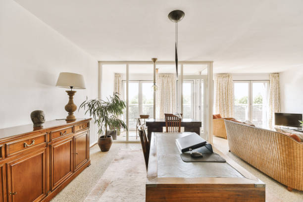 Comfortable wooden chair placed near table with laptop in stylish living light room