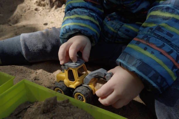 istock Toddler hands playing with sandbox toy excavator. 1409372995