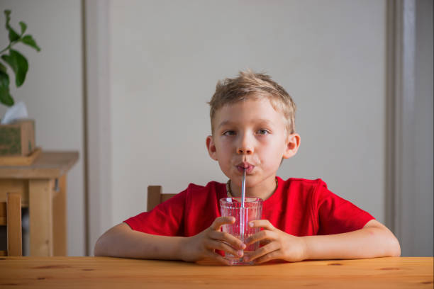 istock Cute boy drinking water through the drinking straw. Lifestyle portrait. 1409373882