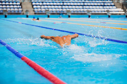 Active mature man swimming at swimming pool, practicing