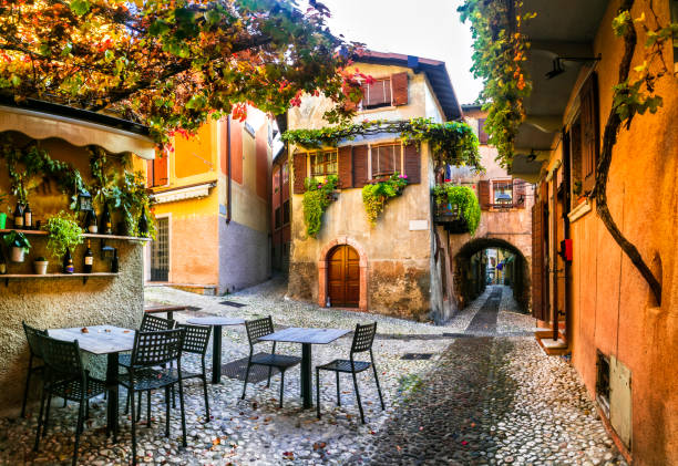 Charming old narrown streets of Italian villages. Malcesine, Garda lake, Italy. Autumn colors, cosy street bars stock photo
