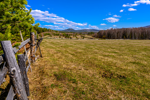 South Ural farm, wooden fence and arable land with a unique landscape, vegetation and diversity of nature in spring.