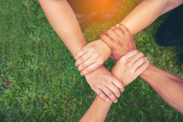 Top View Four hands Diverse multiethnic Partner team together. Close up Teamwork group of Four multiracial people join hands together. Above view Diversity people hand join partner team trust team stock photo