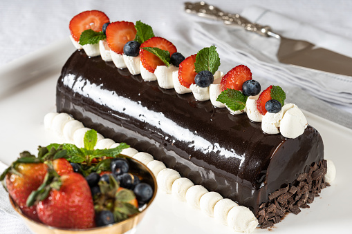 chocolate cake with strawberry, blueberry and mint leaves