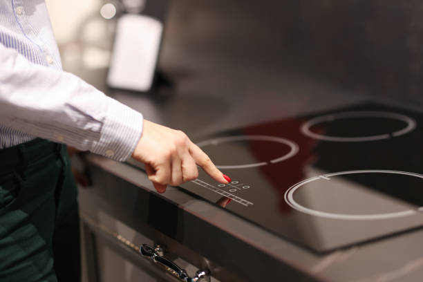 Female finger presses button on touch electric stove Female finger presses button on touch electric stove. Sale of household appliances koncetp glass ceramic stove top stock pictures, royalty-free photos & images