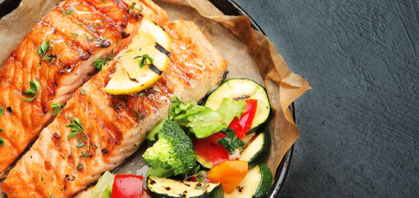 istock Salmon steak with vegetables on dark background. 1409398782