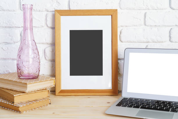 istock Blank picture frame on wooden table with books and laptop 1409413004