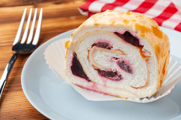 istock Meringue roll cake with cream on wooden table 1409414047