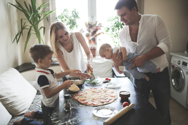 istock parents with two children prepare pizza in cozy 1409416336