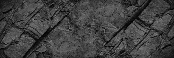 istock Black rock texture. Rough mountain surface with cracks. Close-up. Granite stone background with space for design. 1409416384