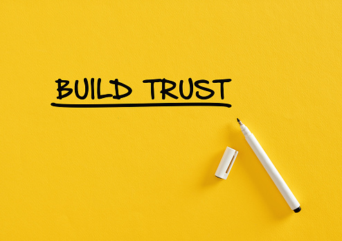 Build trust message written on yellow background with felt tip pen. Business confidence, responsibility and partnership concept.