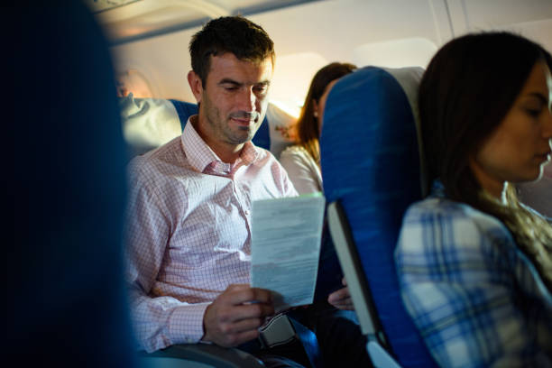 Smiling man reading catalogue in an airplane.