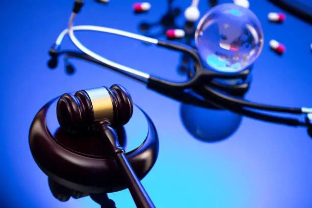 Gavel, legal code and stethoscope on the glass table. Blue light.