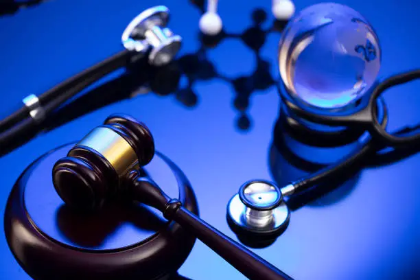 Gavel, legal code and stethoscope on the glass table. Blue light.