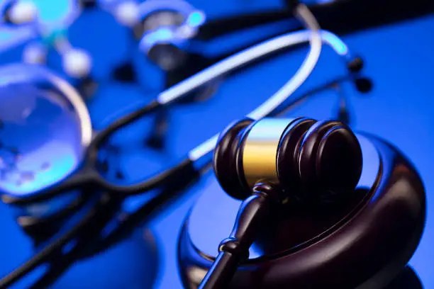 Gavel, legal code and stethoscope on the glass table. Blue light.