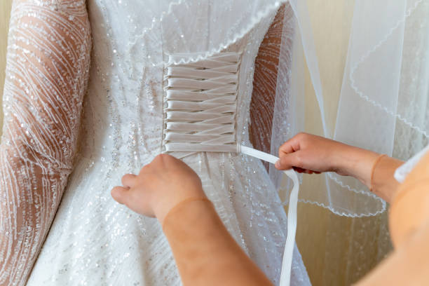 The bride helps to dress in a wedding dress. Lacing stock photo