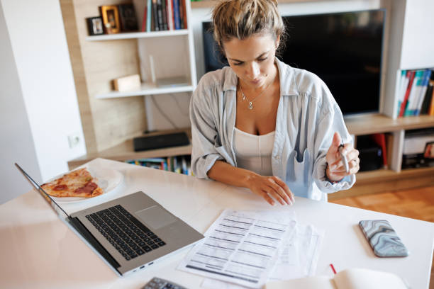Young woman calculating expenses at home stock photo