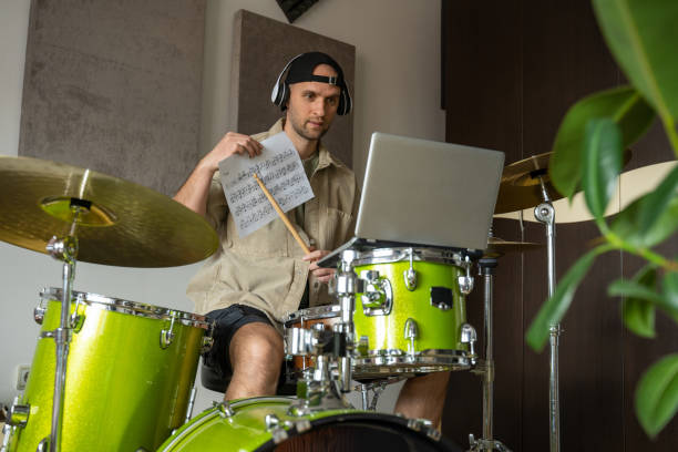 istock Man gives drum lesson via laptop. Guy demonstrates notes 1409423483